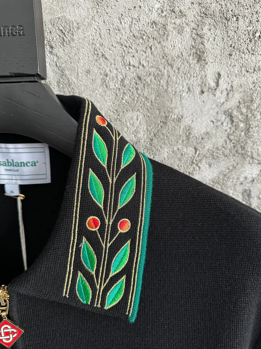Деталь отложного воротника с зелёно-красной вышивкой растительного узора