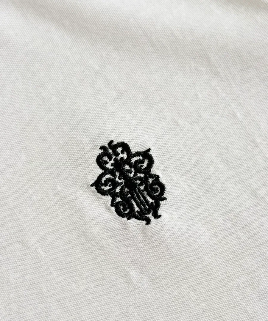 Черная фактурная вышивка на груди белой футболки Chrome Hearts