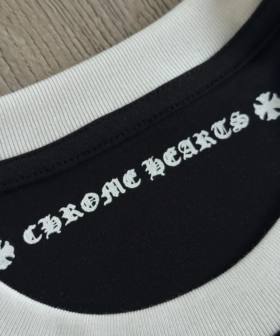 Деталь воротника черной футболки Chrome Hearts с внутренним принтом бренда