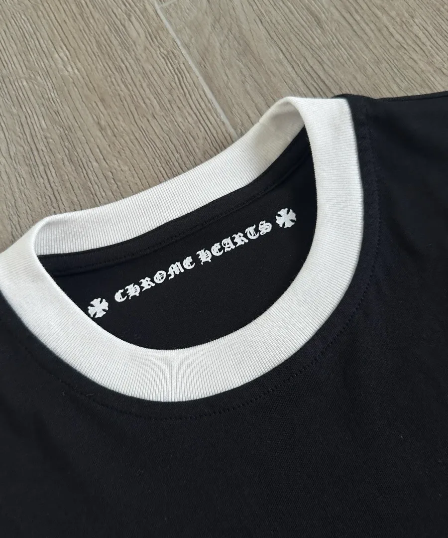 Деталь контрастного белого воротника черной футболки Chrome Hearts