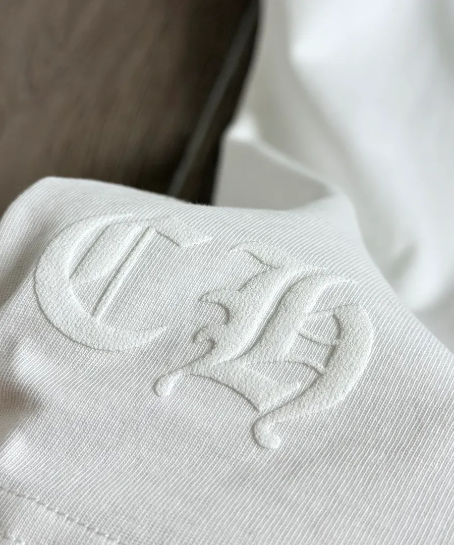 Деталь тиснения CH на белой футболке Chrome Hearts