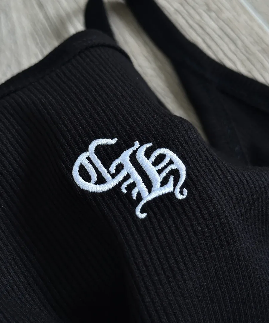 Крупный план вышивки CH на черной майке Chrome Hearts