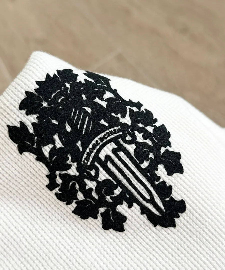 Крупный план черного принта с кинжалом на белом лонгсливе Chrome Hearts