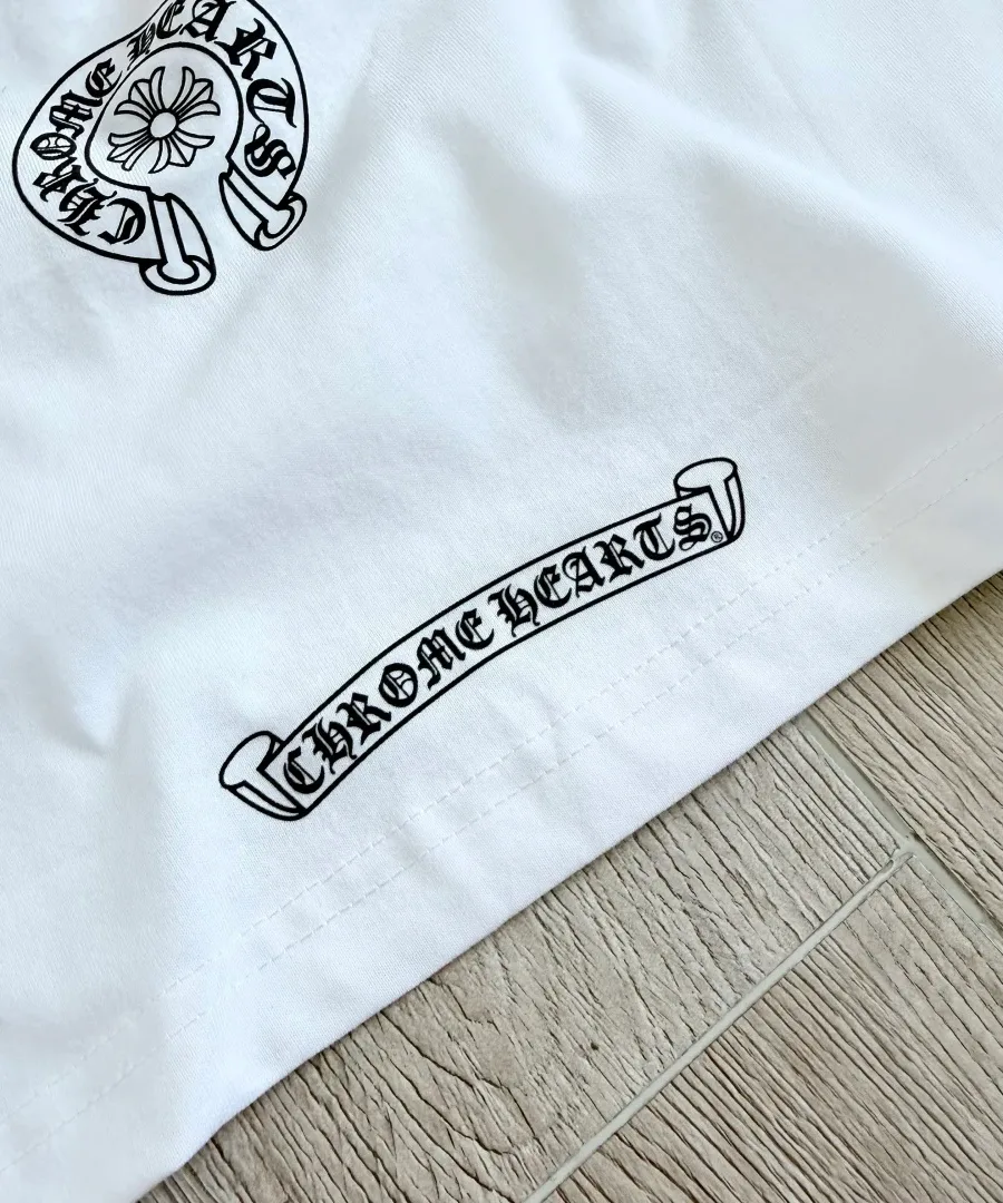 Принт с названием бренда Chrome Hearts на нижнем крае белой футболки