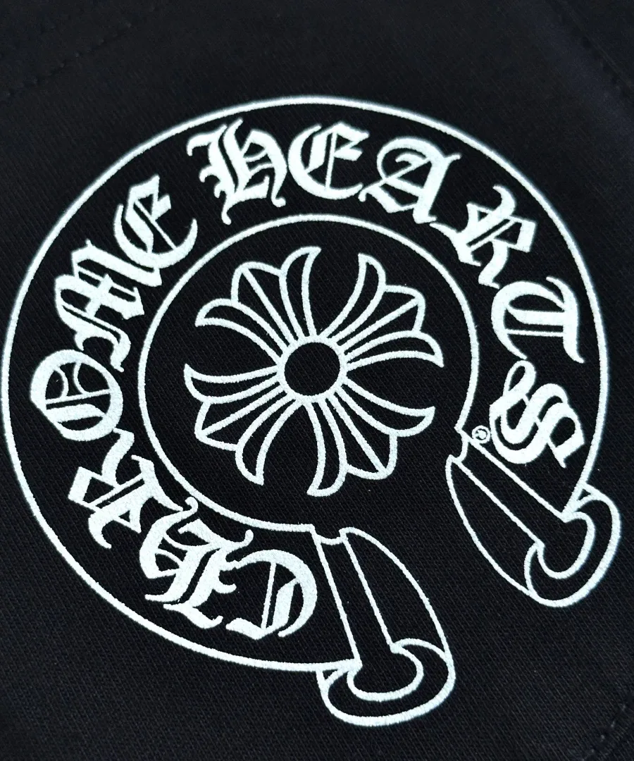 Крупный план белого принта-подковы на кармане черной футболки Chrome Hearts