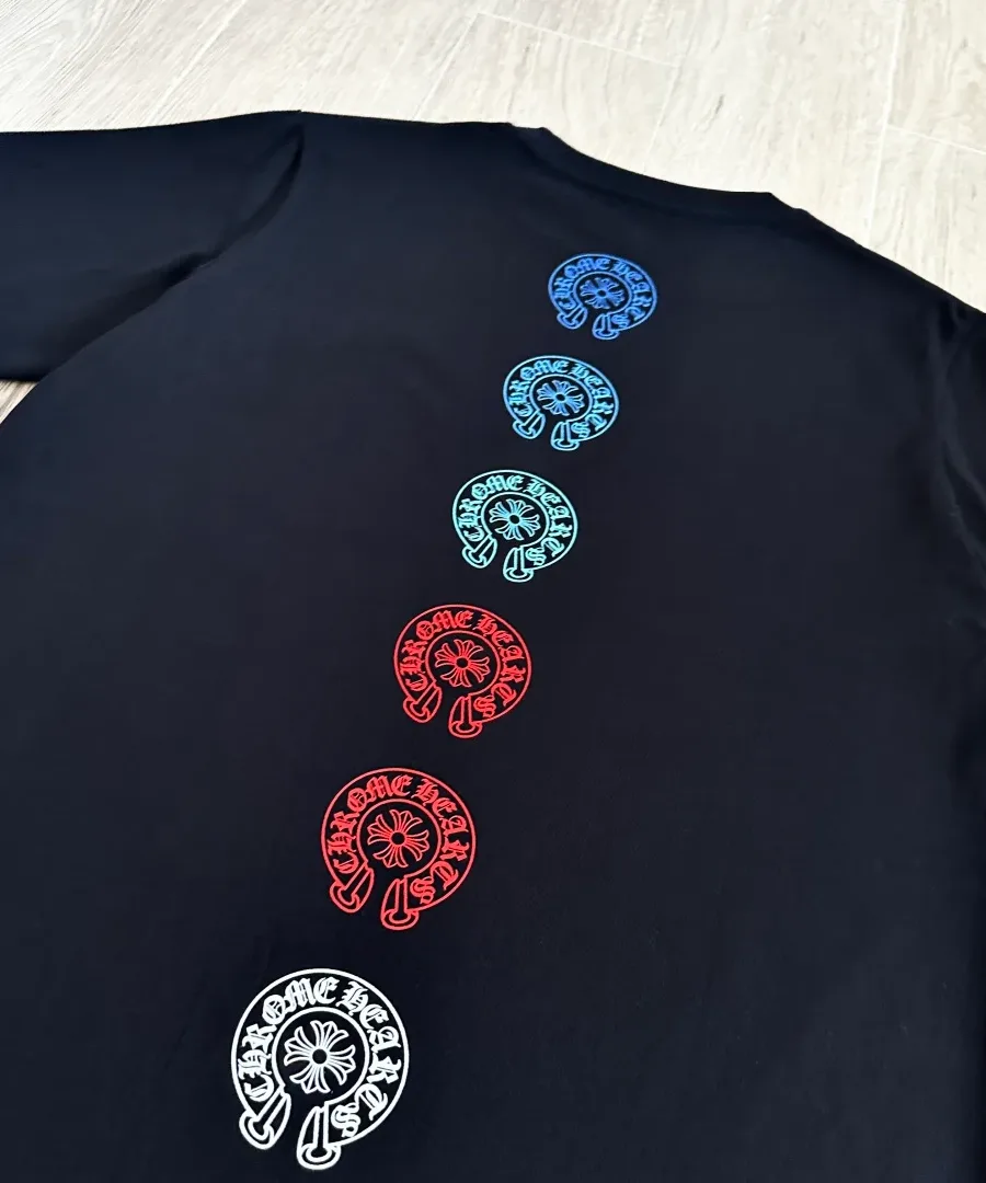 Вертикальный ряд разноцветных логотипов-подков на спине черной футболки Chrome Hearts