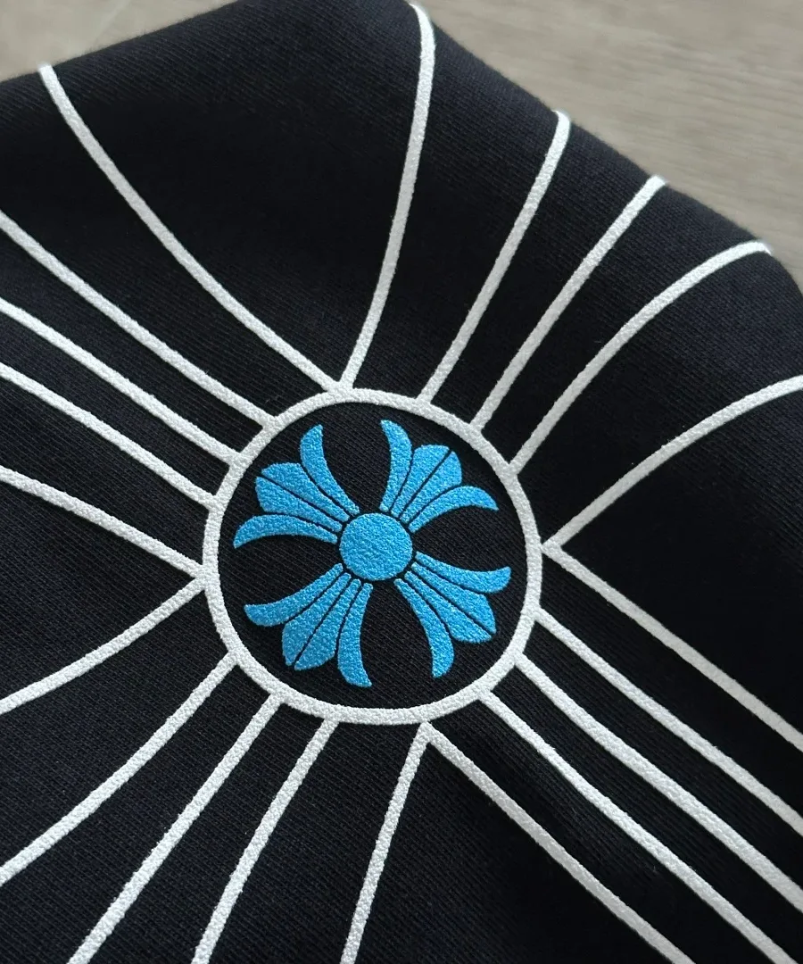 Деталь принта с голубым крестом крупным планом на черном лонгсливе Chrome Hearts