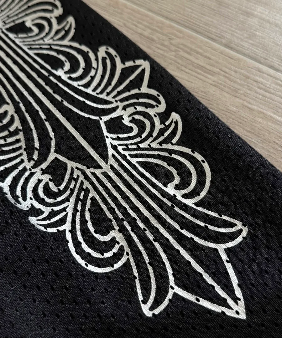 Деталь серебристого принта на черной сетке штанов Chrome Hearts