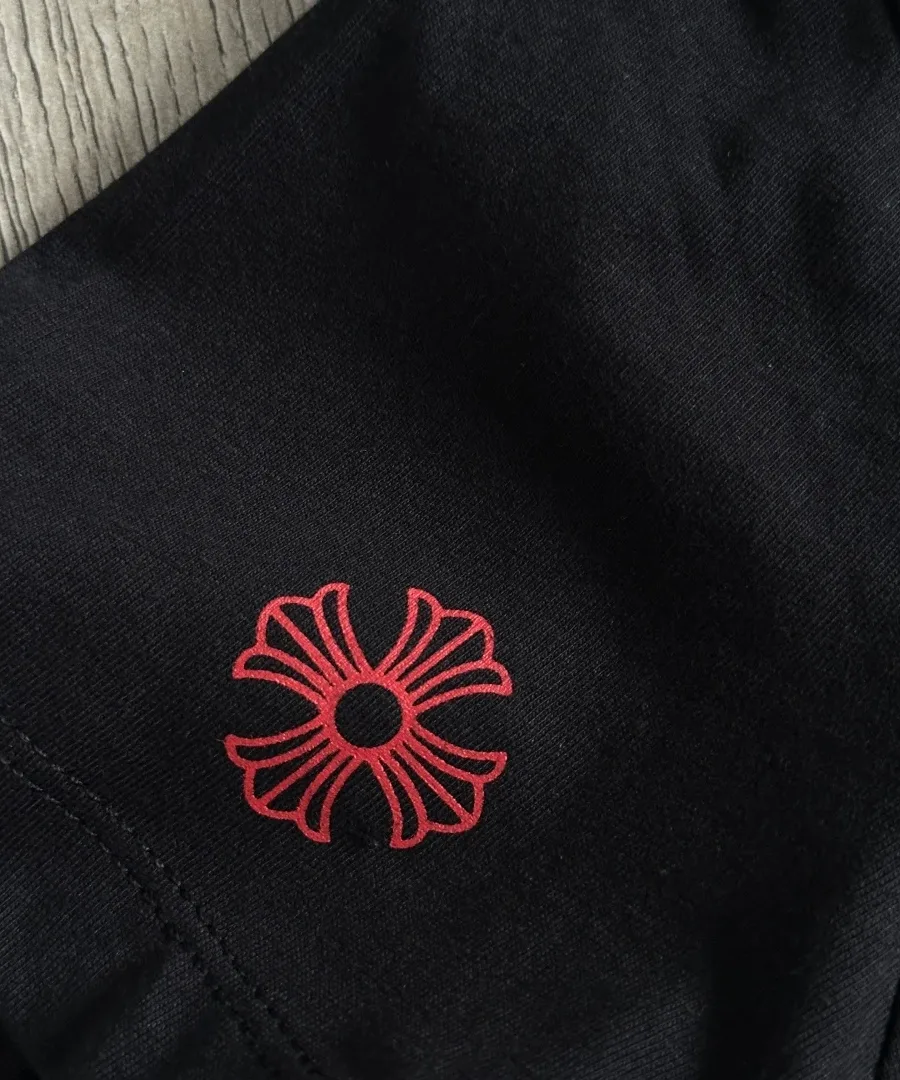 Красный фирменный крест на рукаве чёрной футболки Chrome Hearts
