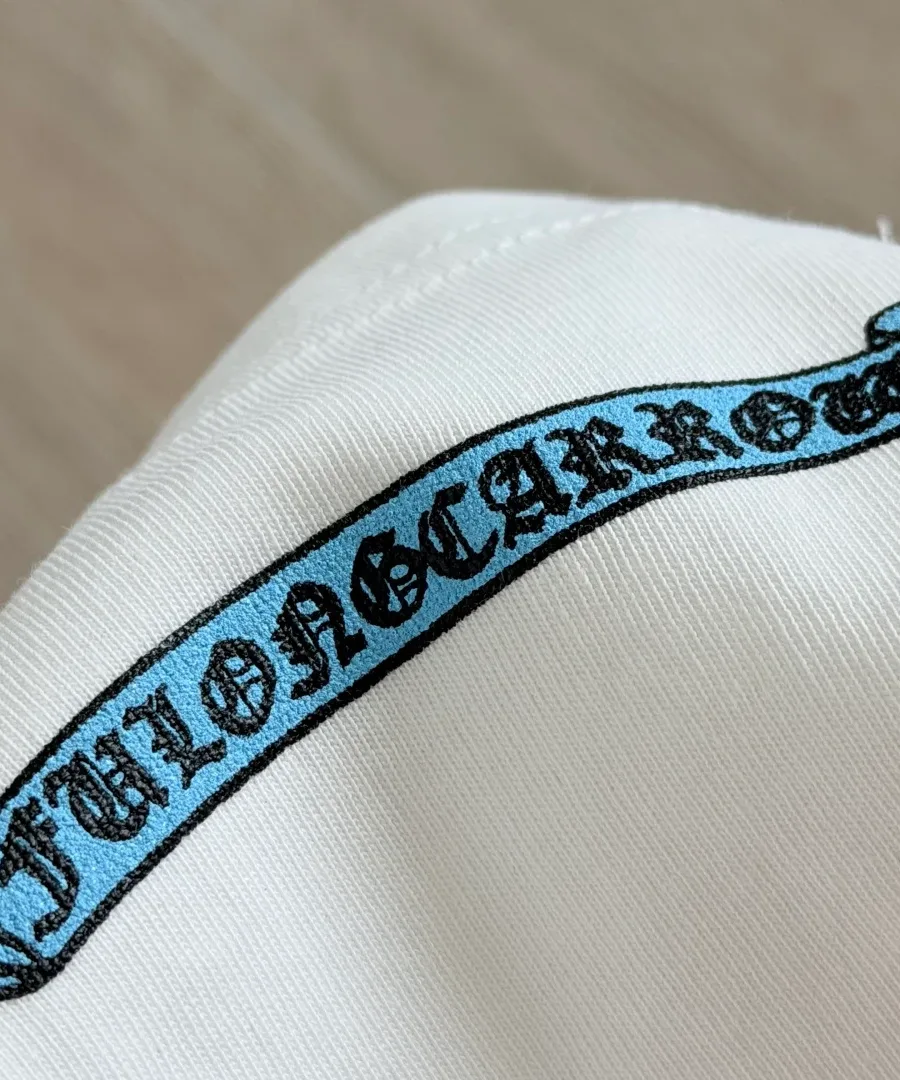 Крупный план принта на кармане белой футболки Chrome Hearts