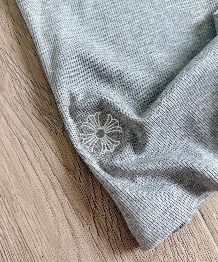 Крупный план вышивки креста на серой майке Chrome Hearts
