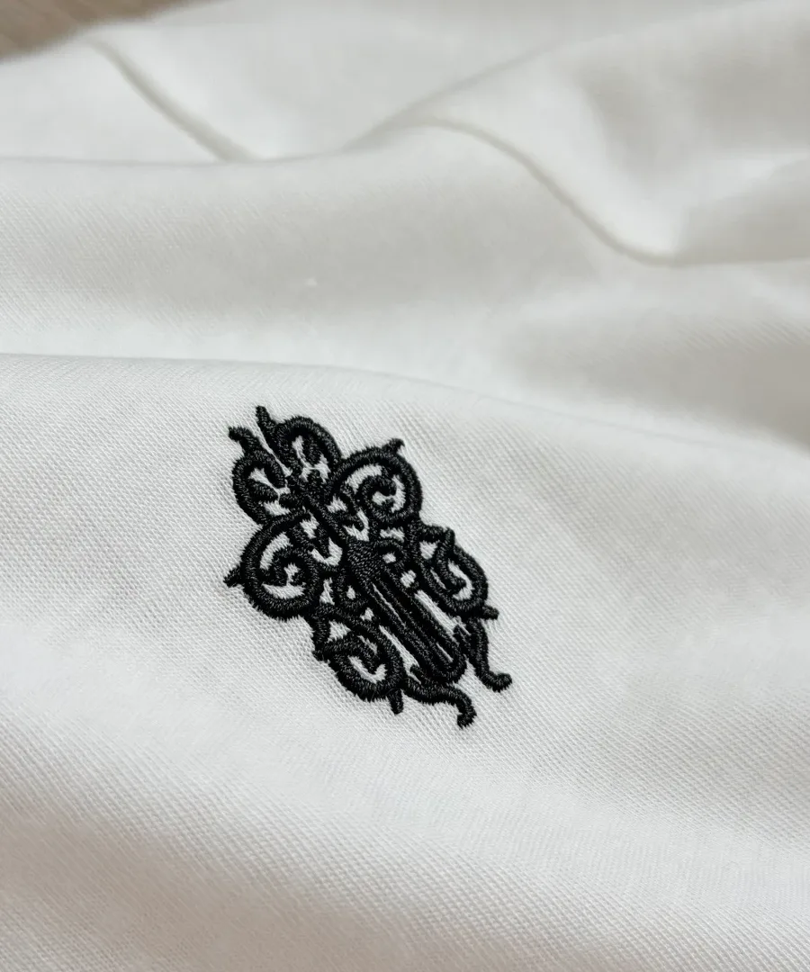 Крупный план вышивки логотипа на груди белого лонгслива Chrome Hearts GRP Y