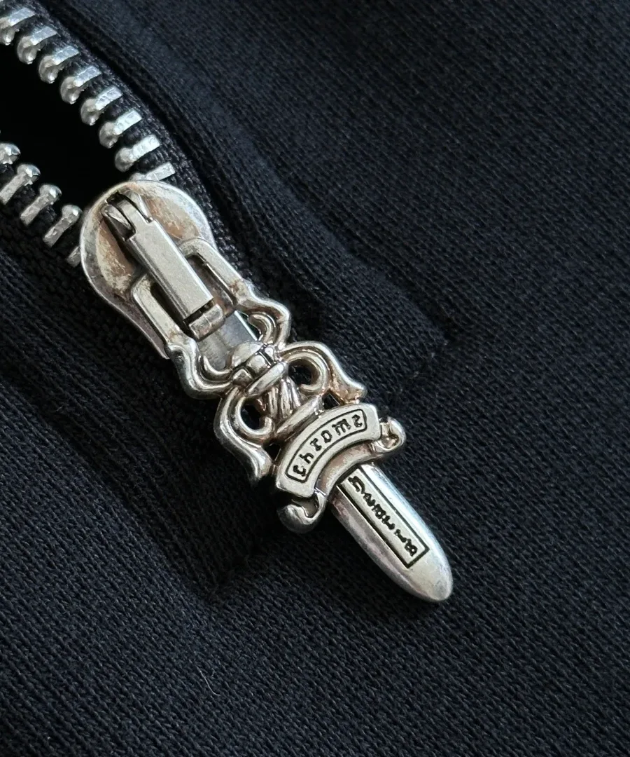 Серебряный пуллер молнии в виде кинжала на толстовке Chrome Hearts