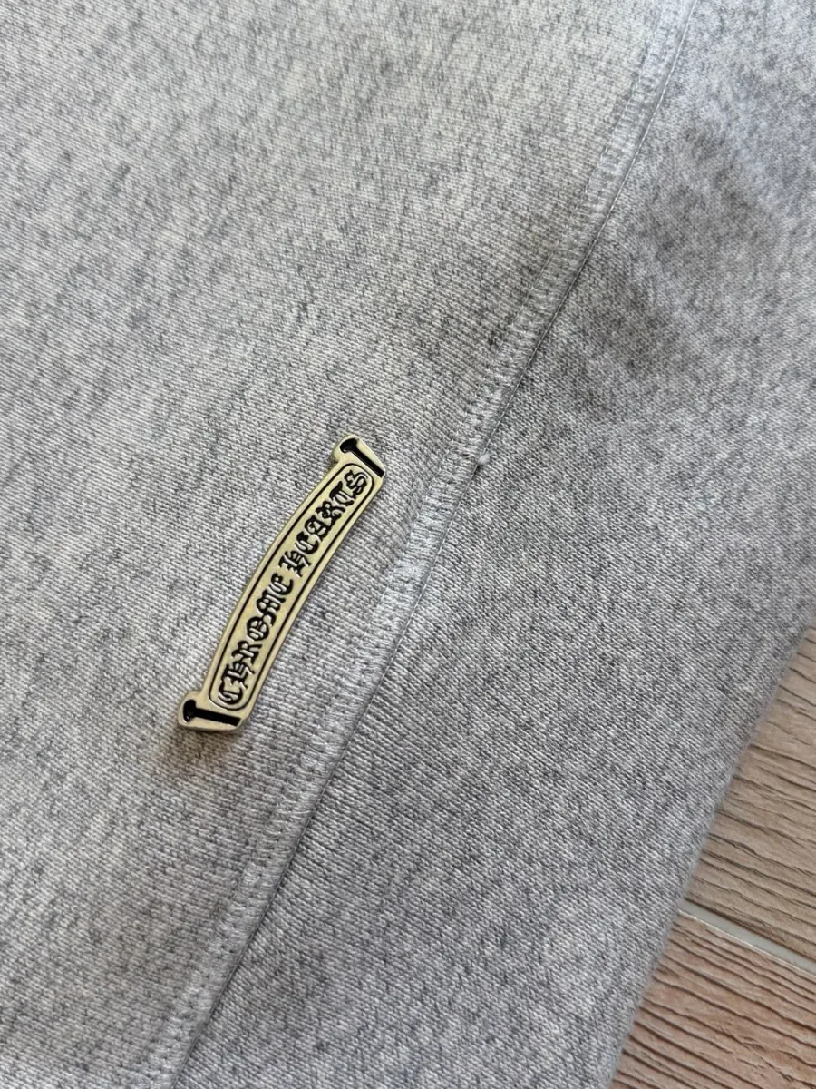 Металлическая плашка с гравировкой Chrome Hearts на нижнем крае худи