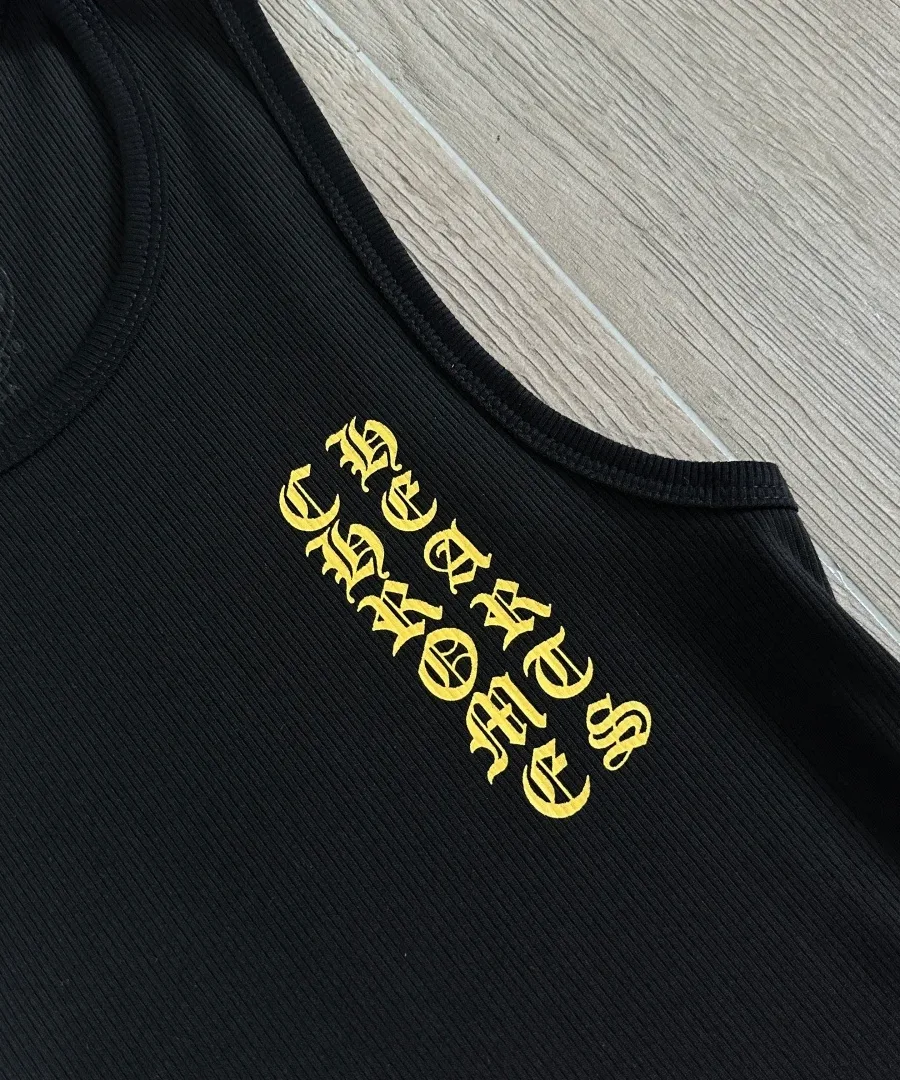 Крупный план желтого готического принта на груди майки Chrome Hearts
