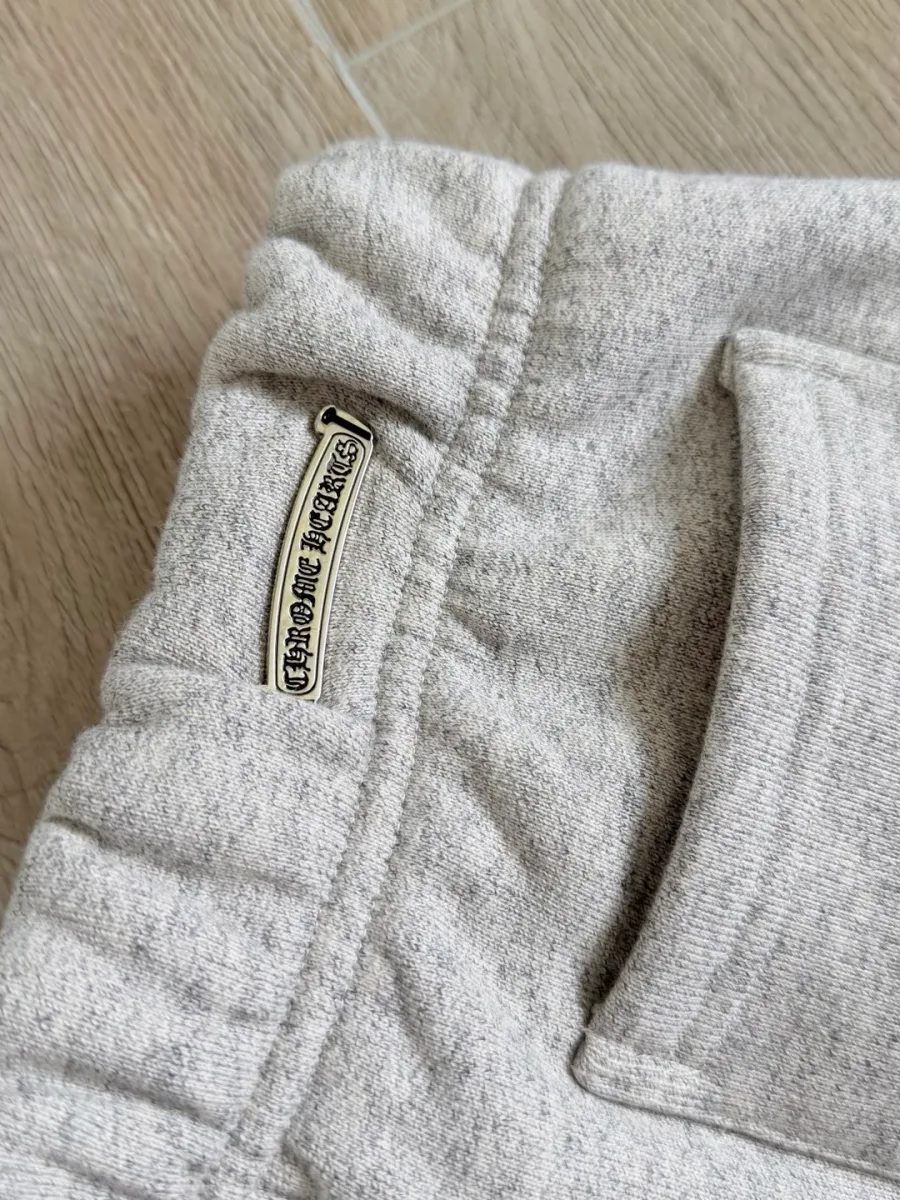 Задний карман серых спортивных штанов Chrome Hearts с серебряной деталью