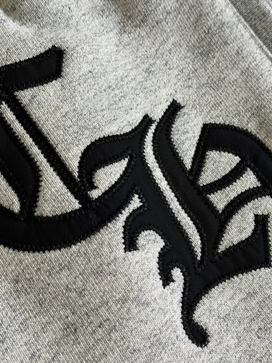 Крупный план вышивки монограммы CH на серых спортивных штанах Chrome Hearts