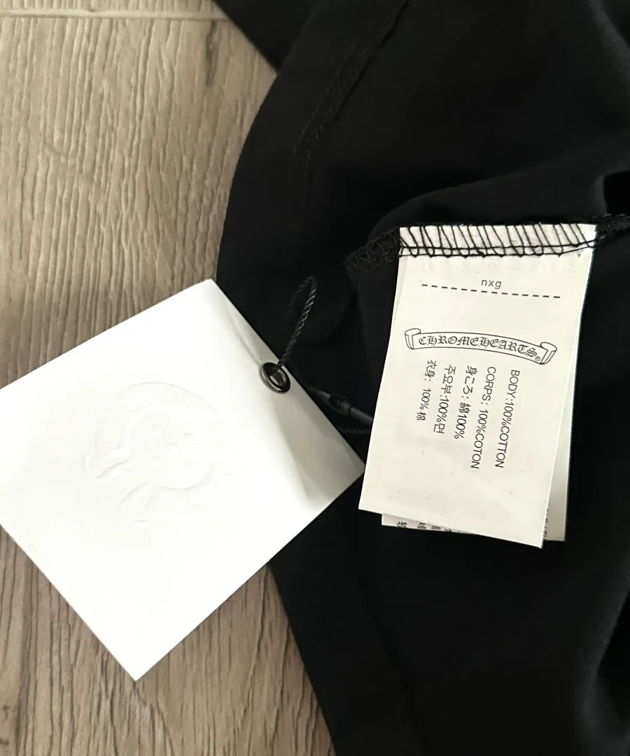 Бирка с составом ткани на черной футболке Chrome Hearts