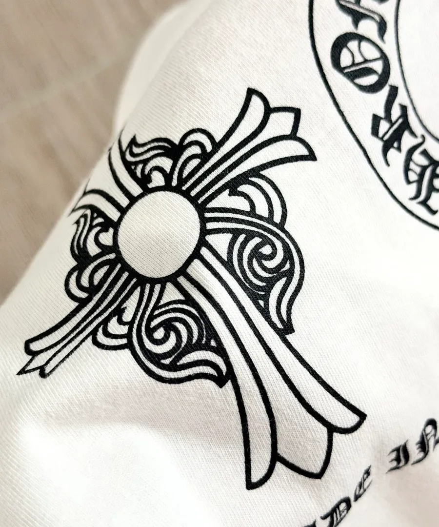 Крупный план принта с геральдическим крестом на белой футболке Chrome Hearts
