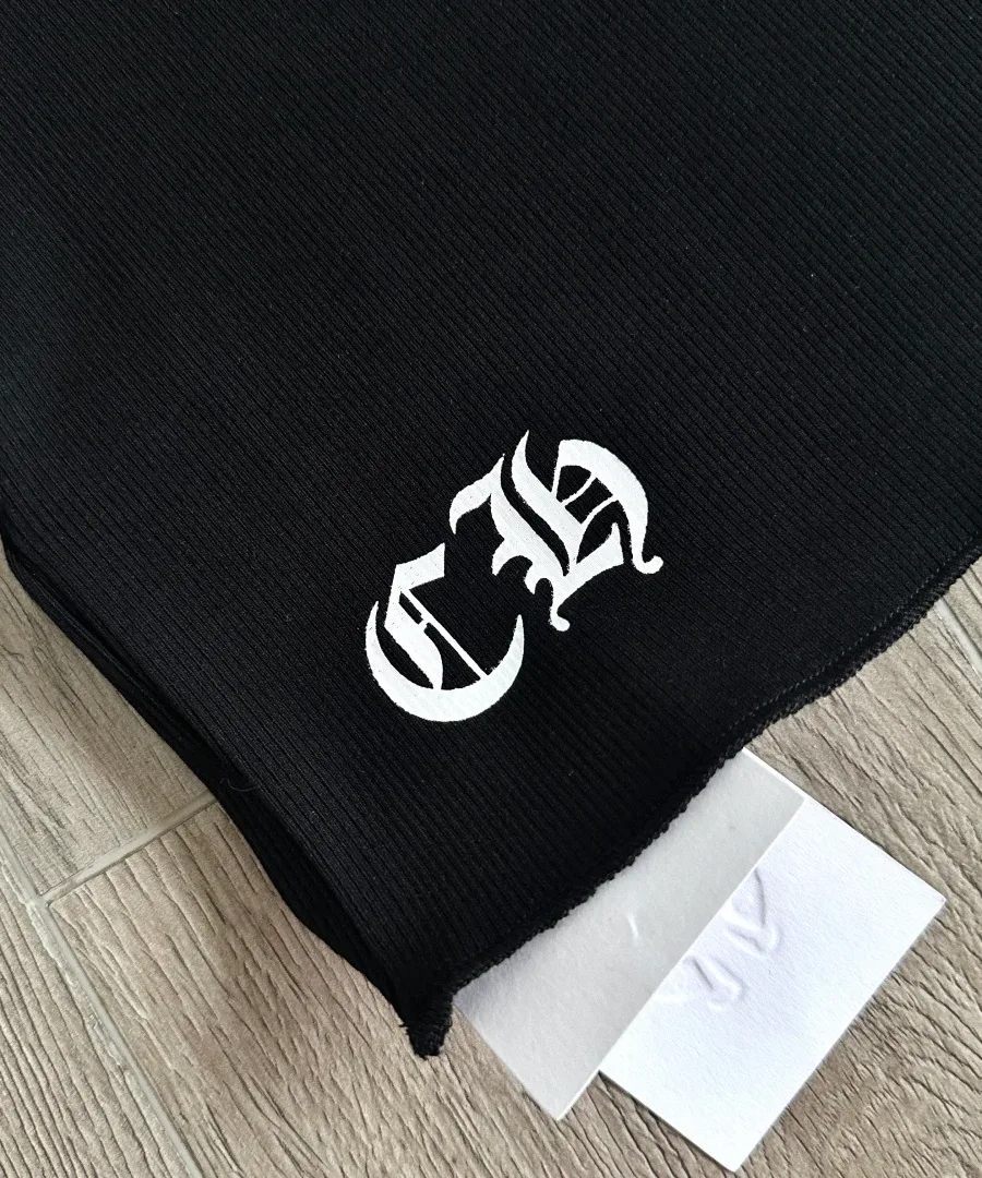 Деталь нижнего края черной майки Chrome Hearts с готическими буквами CH