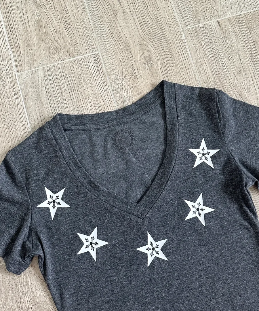 Деталь V-образного выреза серой футболки Chrome Hearts с принтом звезд