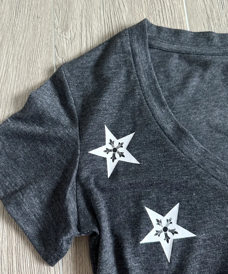 Крупный план принта в виде звезд на плече серой футболки Chrome Hearts