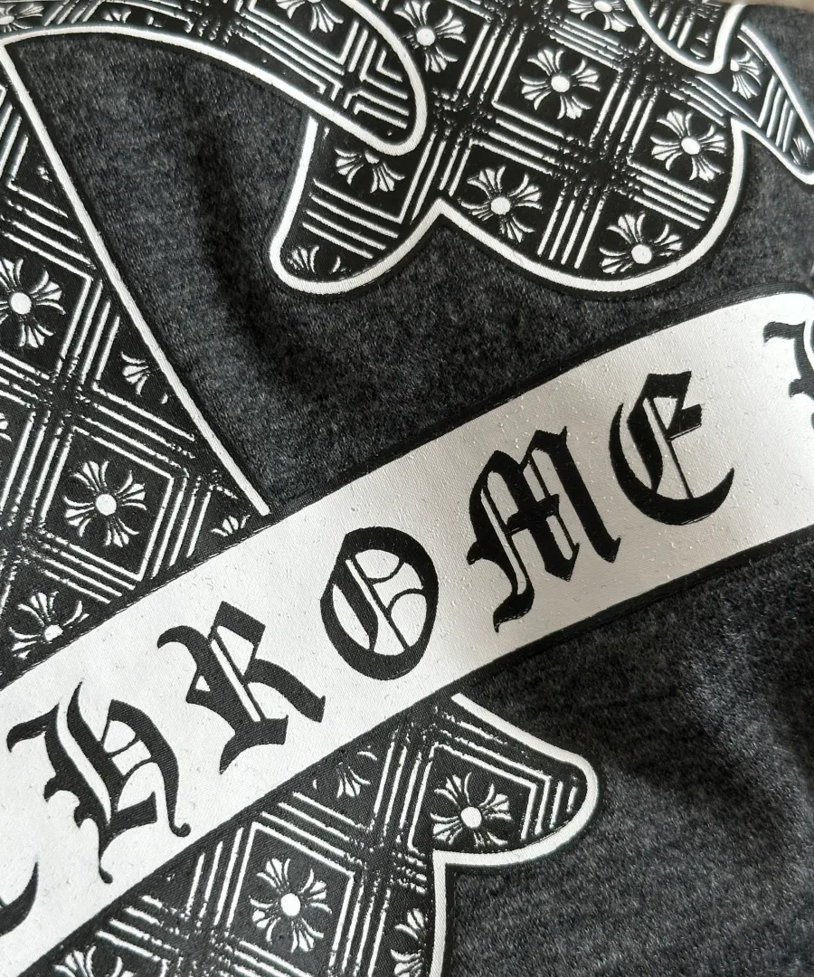 Деталь принта с надписью Chrome Hearts на фоне узорчатого креста