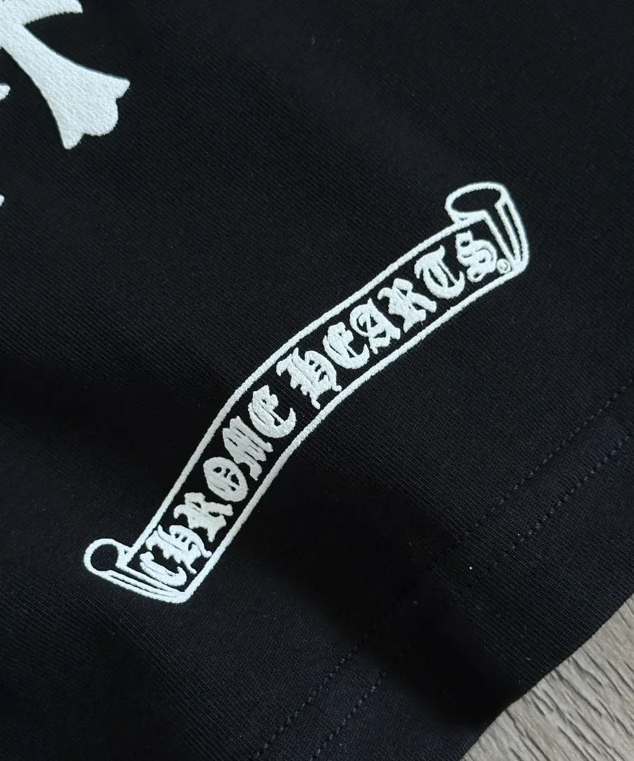 Крупный план логотипа-свитка Chrome Hearts на черной футболке