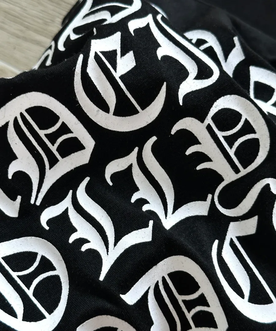 Крупный план готического текстового принта на спине черной футболки Chrome Hearts