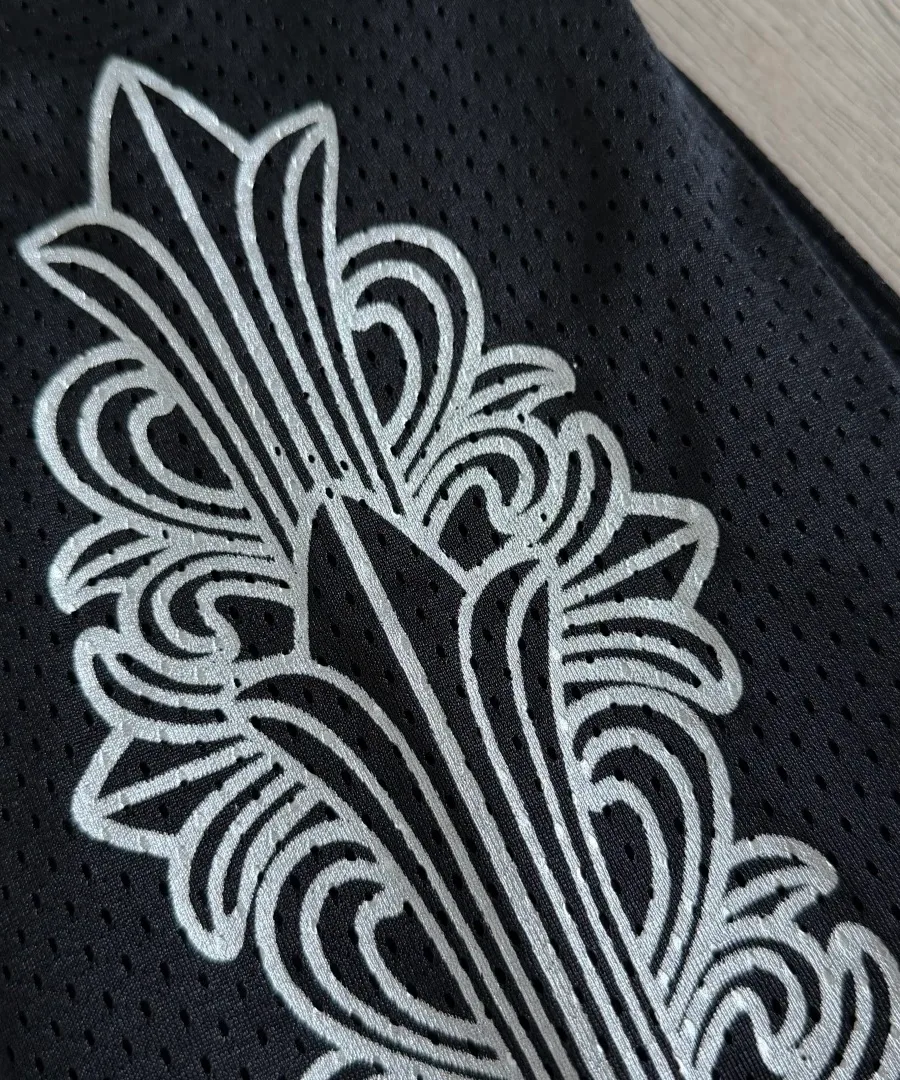 Крупный план серебристого готического принта на рукаве лонгслива Chrome Hearts