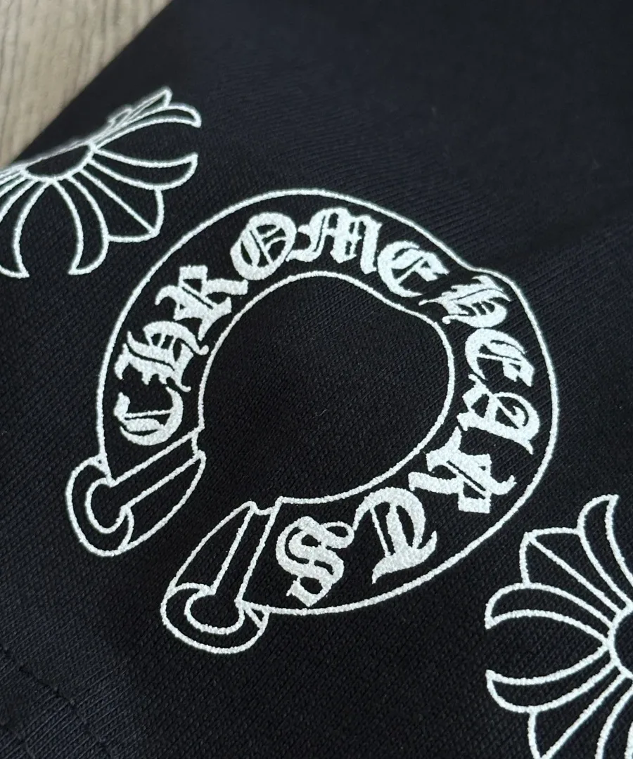 Крупный план принта на рукаве черной футболки Chrome Hearts
