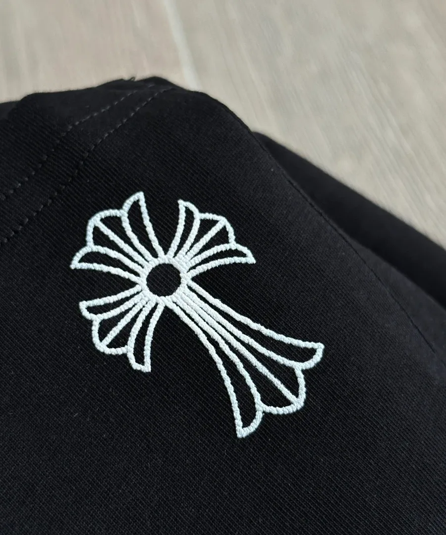 Деталь вышивки креста на черной футболке Chrome Hearts