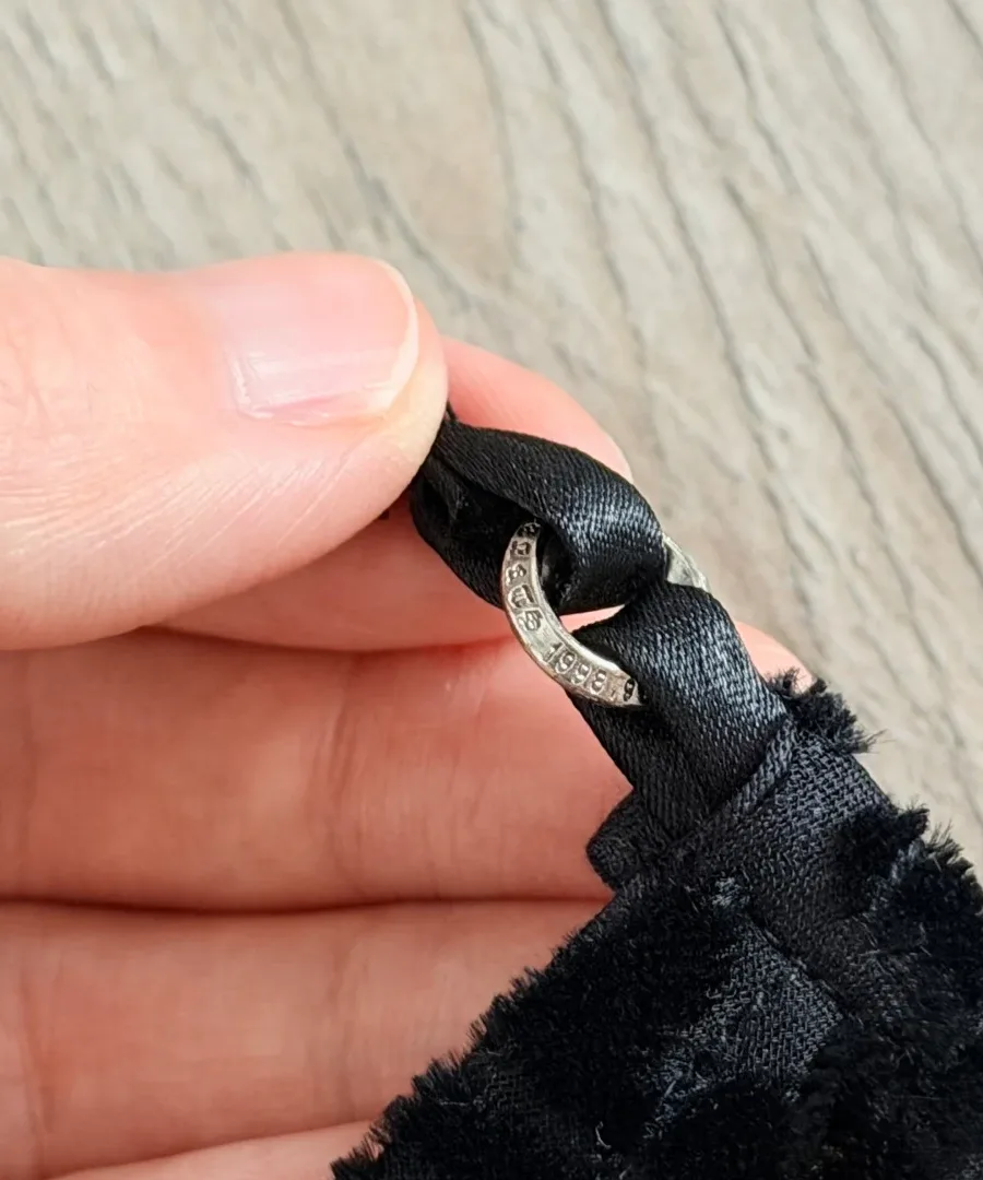 Деталь серебряного кольца на бретели топа Chrome Hearts в руке