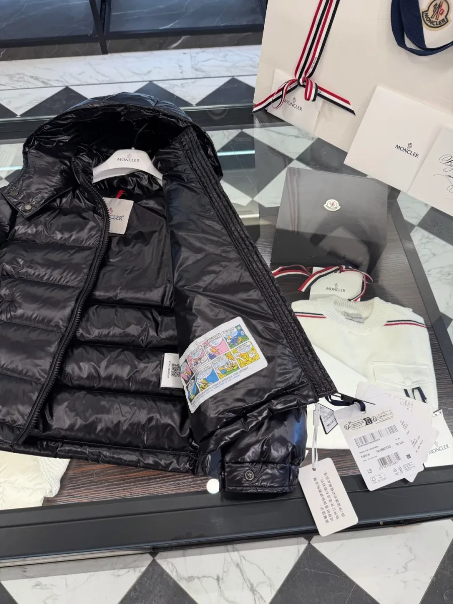 Чёрный пуховик Moncler Maya на плечиках на фоне рейла