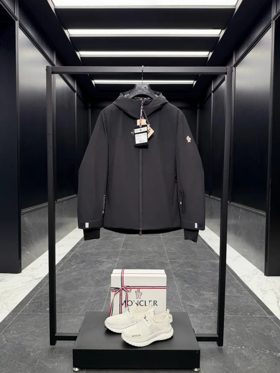Чёрный пуховик Moncler Grenoble с капюшоном и гладким верхом Gore-Tex, общий вид спереди на стойке
