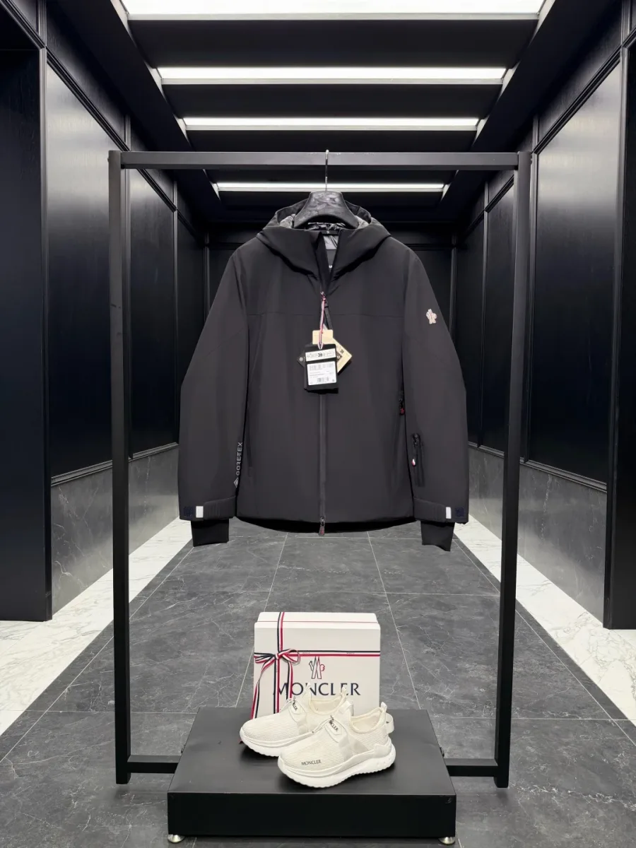 Чёрный мужской пуховик Moncler Grenoble на молнии с навесными бирками, фронтальный ракурс на вешалке