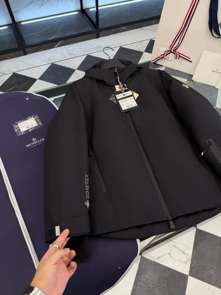 Крупный план правого рукава чёрного пуховика Moncler Grenoble с принтом Gore-Tex и хлястиком на липучке