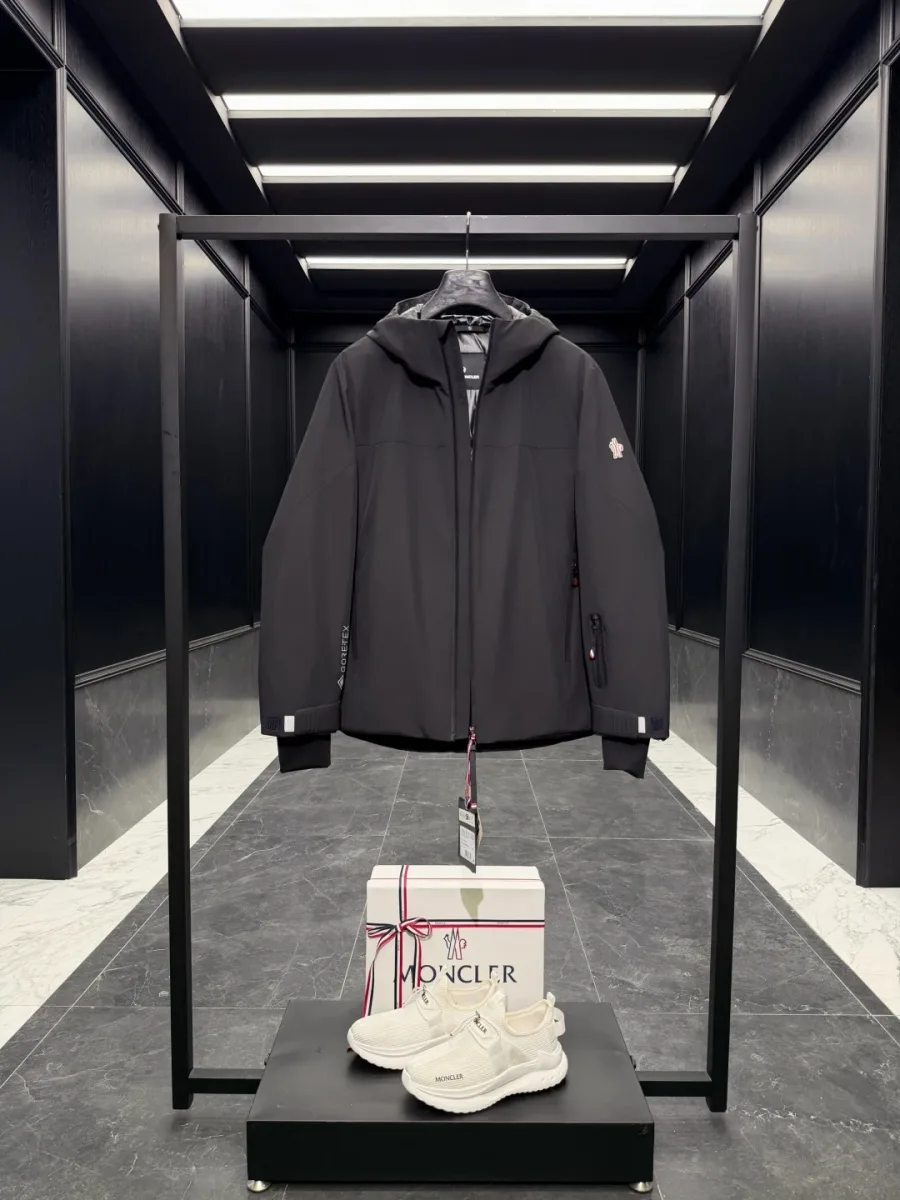 Чёрная утеплённая куртка Moncler Grenoble с застёгнутым воротником-стойкой, вид спереди в полный рост