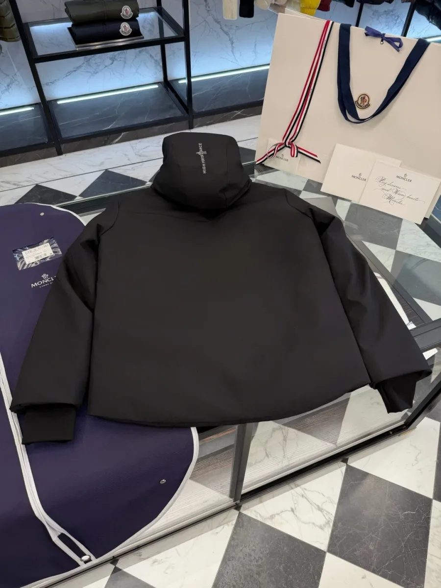 Вид сзади на разложенный чёрный пуховик Moncler Grenoble с надписью High Performance на капюшоне