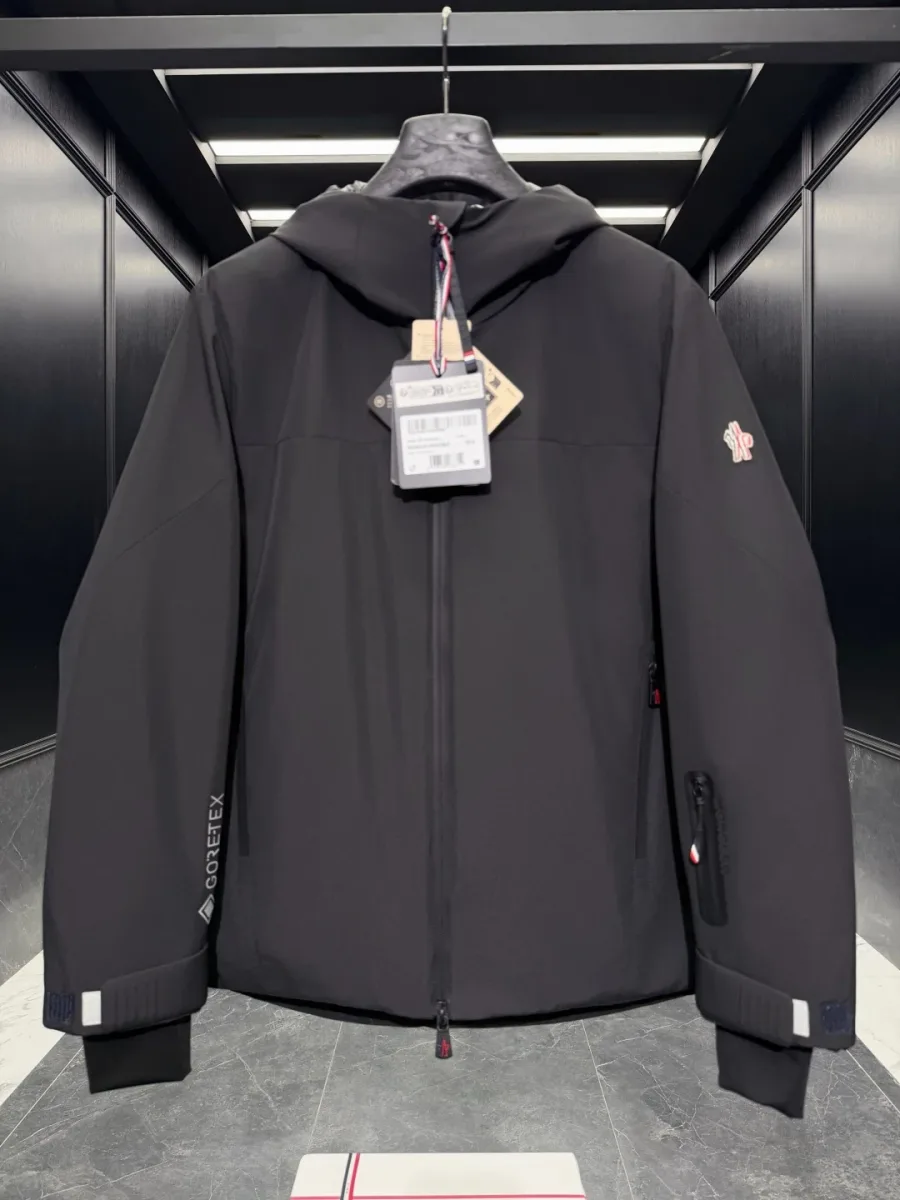 Чёрный пуховик Moncler Grenoble с логотипом на левом плече и надписью Gore-Tex на рукаве, крупный план