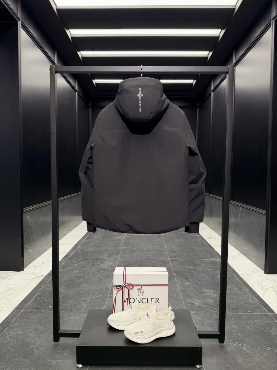 Чёрный пуховик Moncler Grenoble с вертикальной надписью High Performance на капюшоне, вид со спины