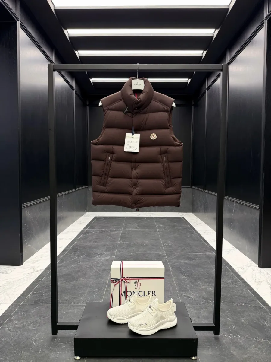 Коричневый пуховый жилет Moncler на вешалке, общий вид спереди в интерьере