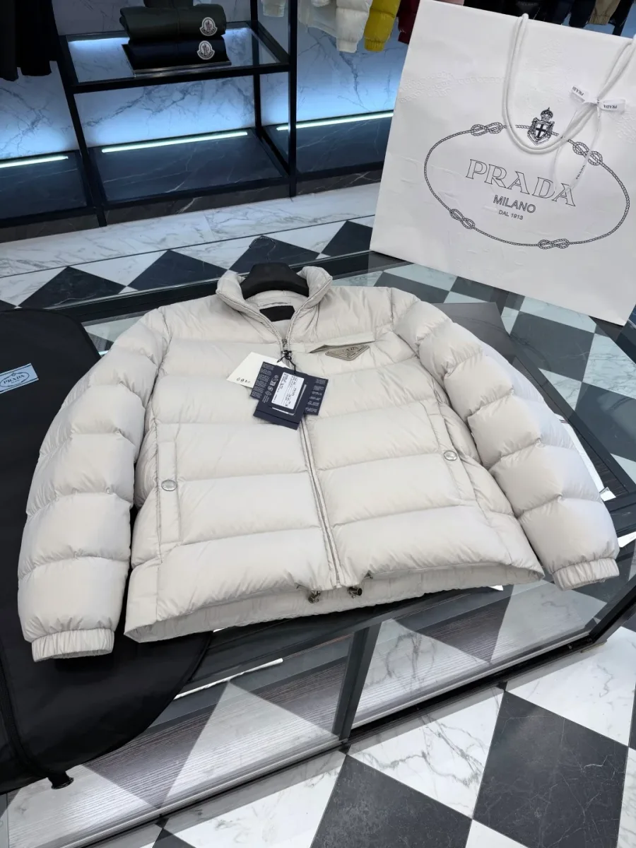Общий вид спереди на светло-бежевый пуховик Prada в горизонтальной раскладке на столе