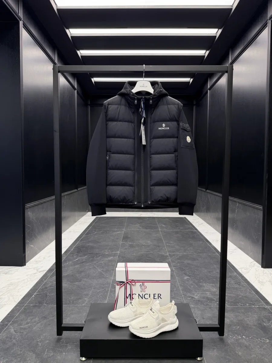 Чёрный комплект из куртки и жилета Moncler на вешалке в интерьере, общий вид спереди