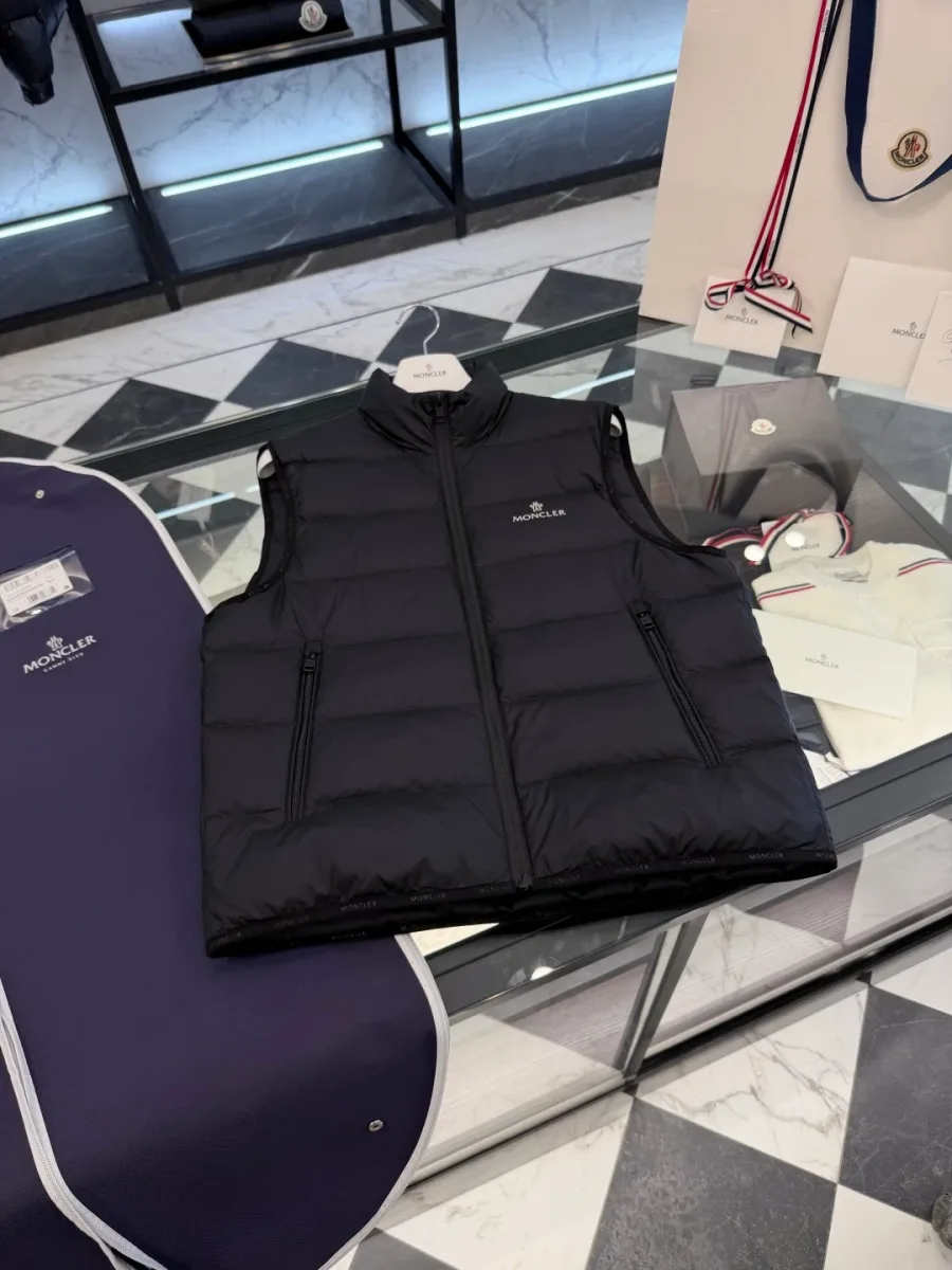Чёрный стеганый пуховый жилет Moncler, разложенный на столе, ракурс под углом