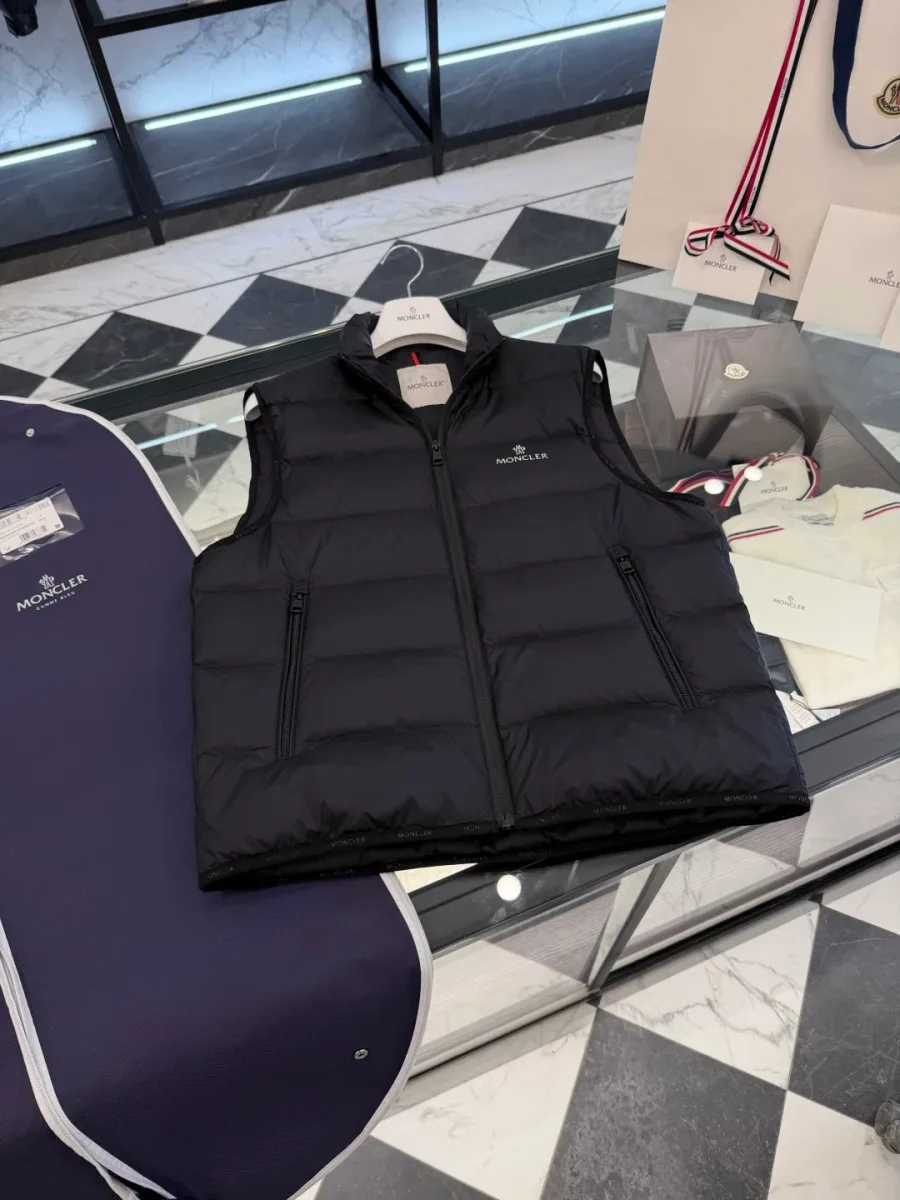 Мужской пуховый жилет Moncler чёрного цвета на стеклянной витрине, вид спереди