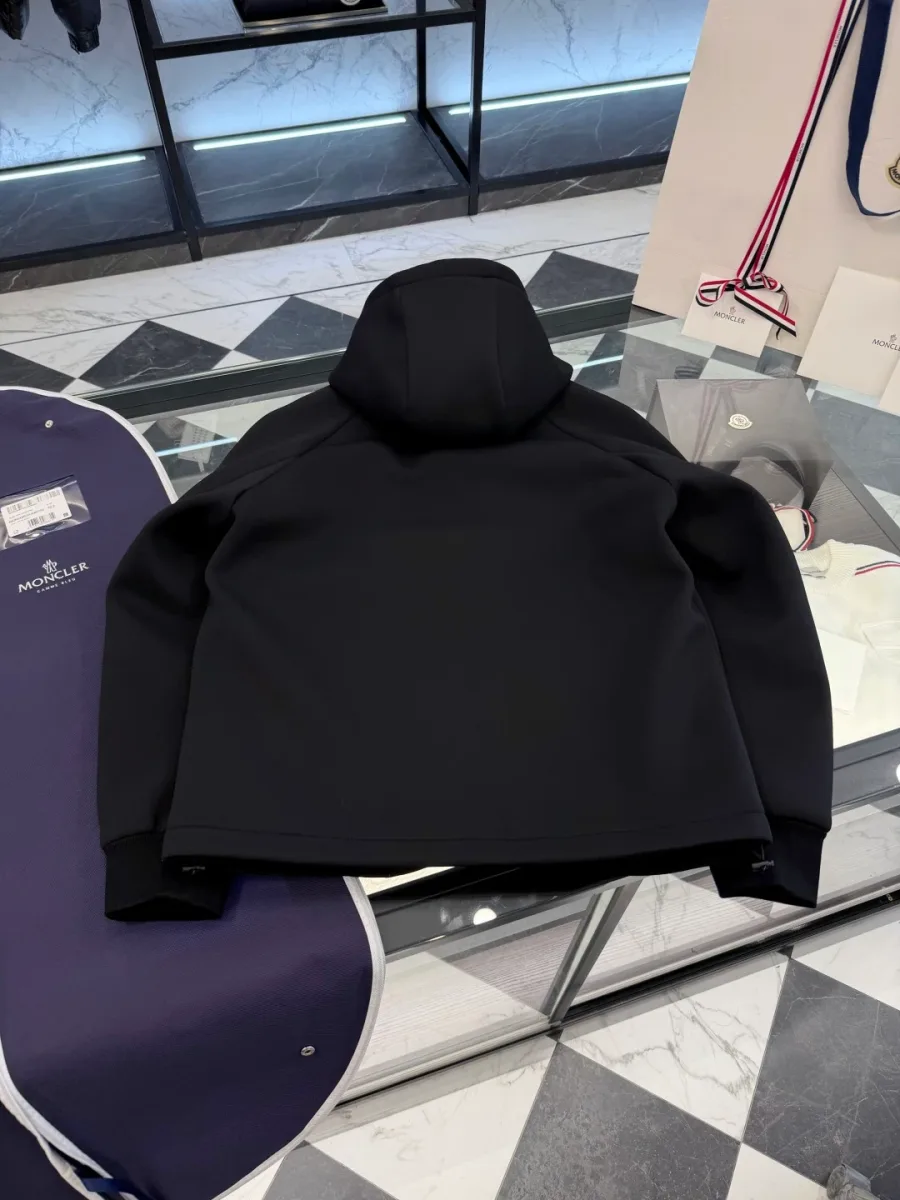 Чёрная трикотажная куртка Moncler с капюшоном, вид со спины на столе