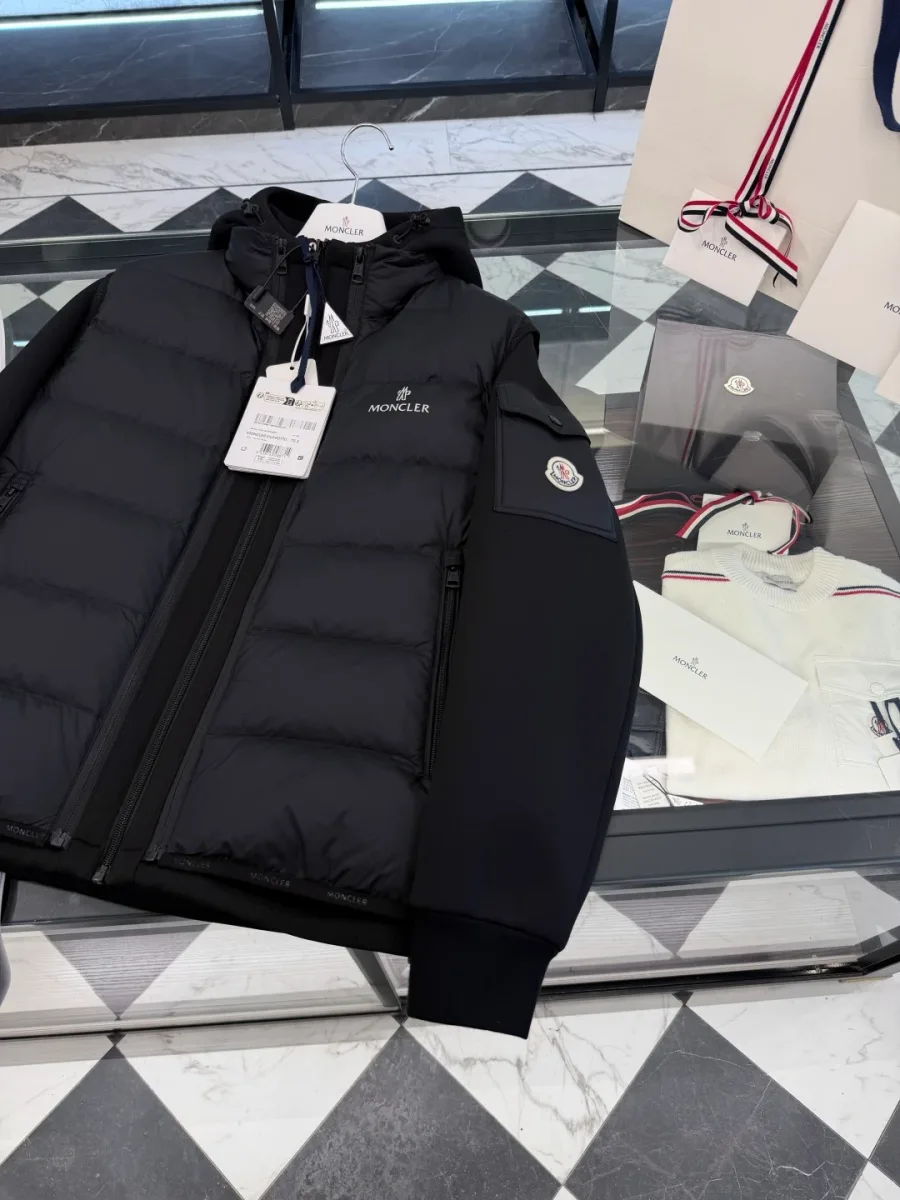 Чёрная куртка с надетым стеганым жилетом Moncler на столе, ракурс сверху