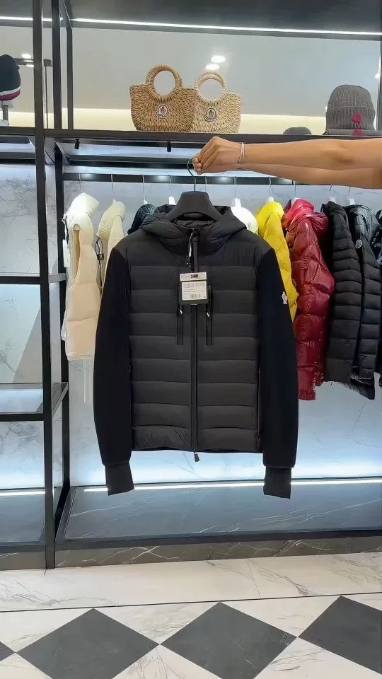 Чёрный пуховик Moncler на вешалке в интерьере бутика, вид спереди