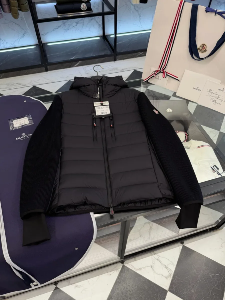 Чёрная пуховая куртка Moncler на стеклянном столе на фоне чехла, вид спереди